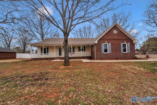 single story home featuring covered porch, brick siding, a front lawn, and fence