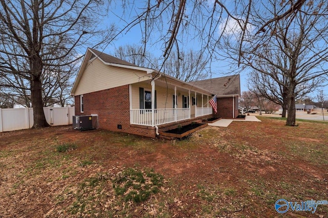 view of side of home with a porch, crawl space, brick siding, and central AC