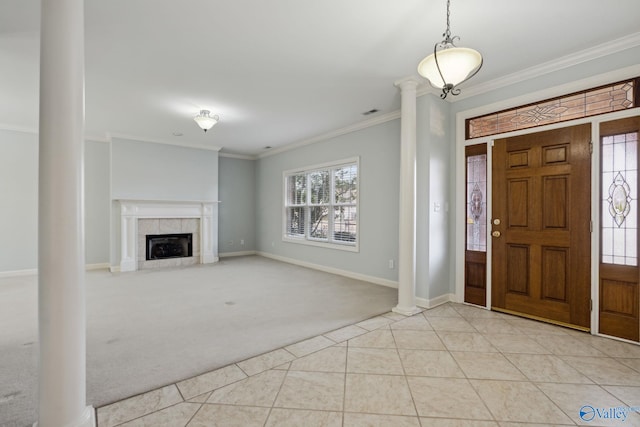 foyer with a tiled fireplace, ornamental molding, light tile patterned floors, and decorative columns