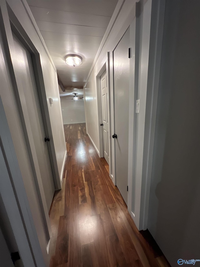 corridor featuring crown molding, dark wood finished floors, and baseboards