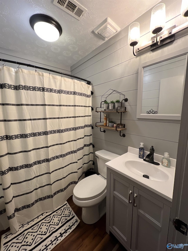 full bathroom featuring visible vents, toilet, wood finished floors, a textured ceiling, and vanity