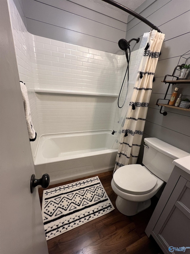 bathroom with toilet, shower / bath combo with shower curtain, wood walls, vanity, and wood finished floors