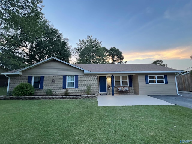 single story home with a patio area, brick siding, and a front lawn