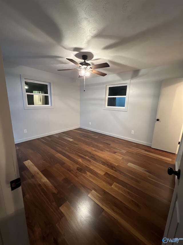 unfurnished room featuring dark wood-style floors, ceiling fan, and baseboards