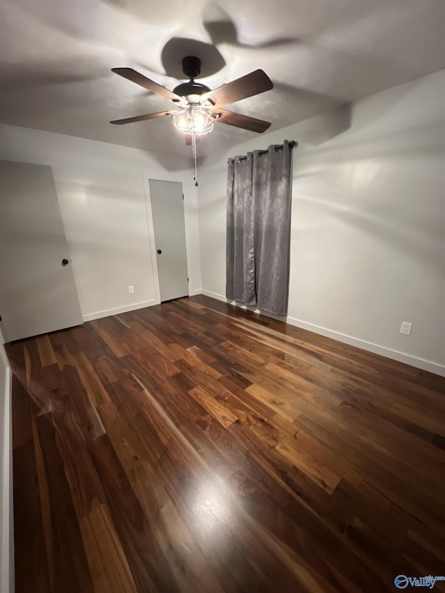 interior space featuring dark wood-style flooring, ceiling fan, and baseboards