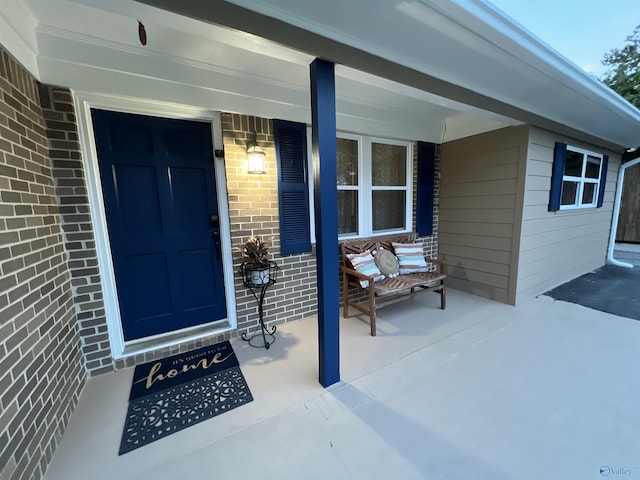 entrance to property featuring covered porch and brick siding