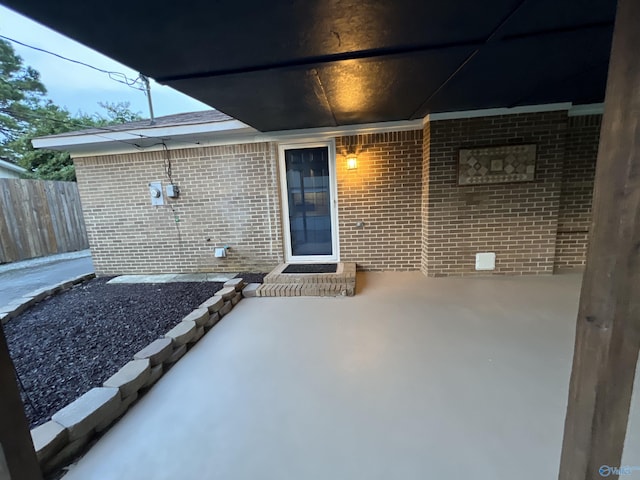 entrance to property featuring brick siding and fence