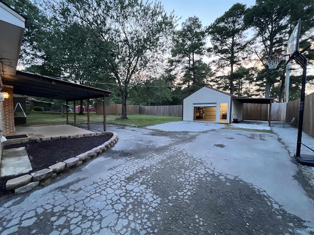 view of yard featuring driveway, a garage, fence, and an outdoor structure