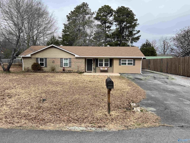 ranch-style house featuring brick siding, driveway, and fence