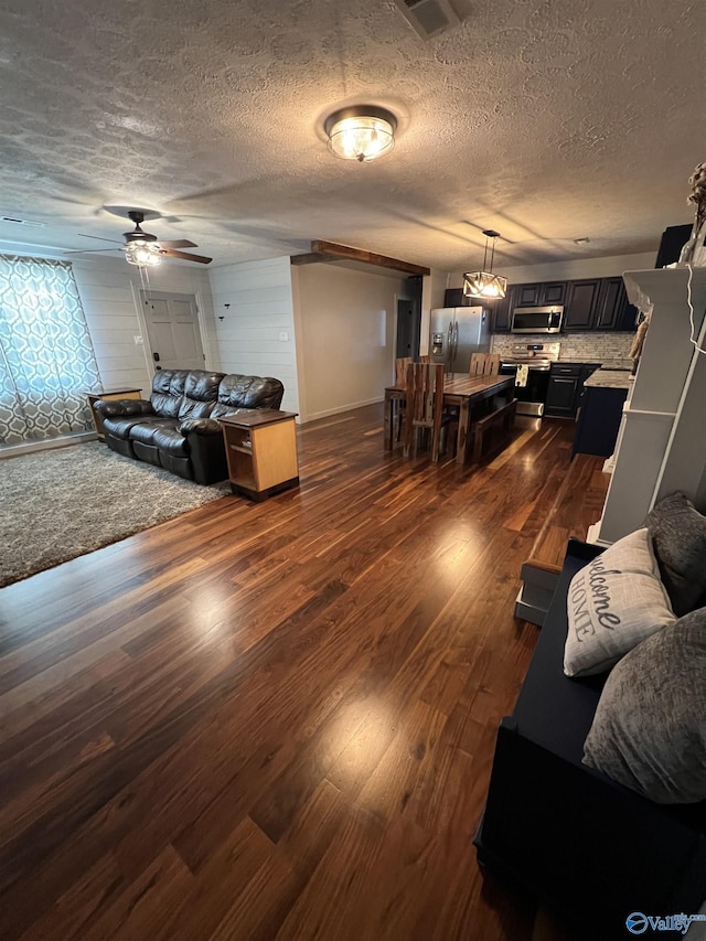 living area with a textured ceiling, visible vents, dark wood finished floors, and a ceiling fan