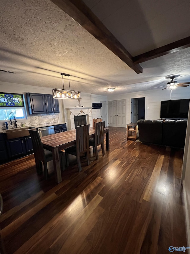 dining room with a textured ceiling, a ceiling fan, dark wood finished floors, and beam ceiling