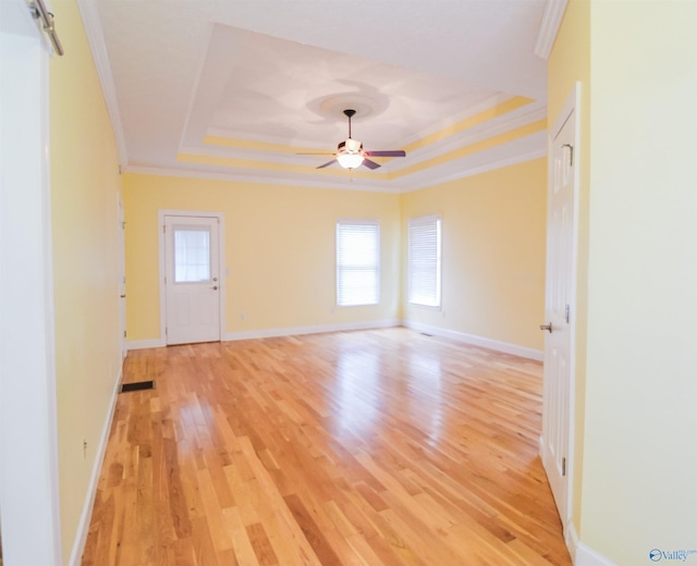 unfurnished room with a wealth of natural light, a tray ceiling, light hardwood / wood-style floors, and ceiling fan