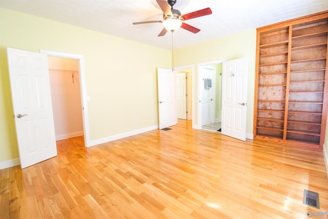 unfurnished bedroom featuring light hardwood / wood-style floors, ceiling fan, a walk in closet, and a closet