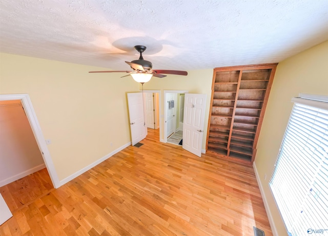 unfurnished bedroom with light hardwood / wood-style flooring, a textured ceiling, and ceiling fan