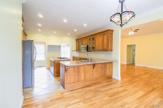 kitchen with light hardwood / wood-style floors, sink, kitchen peninsula, a kitchen breakfast bar, and appliances with stainless steel finishes