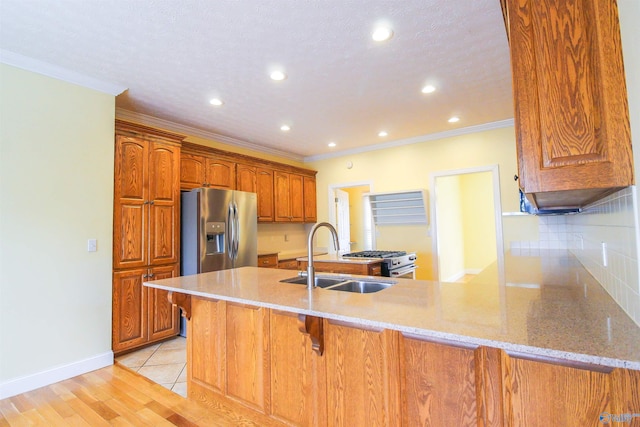 kitchen featuring ornamental molding, sink, kitchen peninsula, appliances with stainless steel finishes, and light wood-type flooring