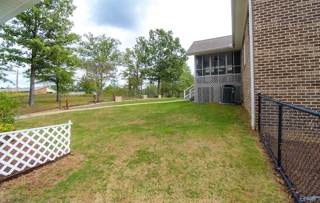 view of yard featuring a sunroom and central air condition unit