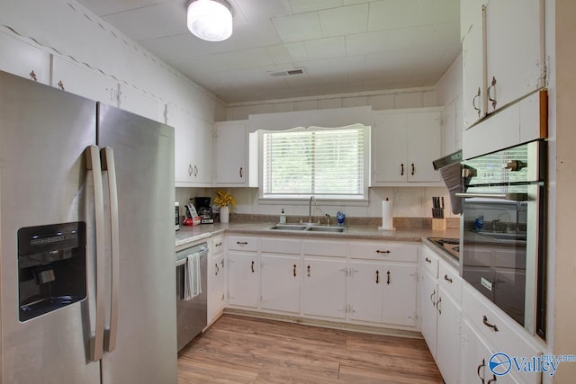 7615 Scottsboro Hwy, Scottsboro, AL 35769 - kitchen featuring white cabinets, a sink, light wood-style floors, stainless steel appliances, and light countertops