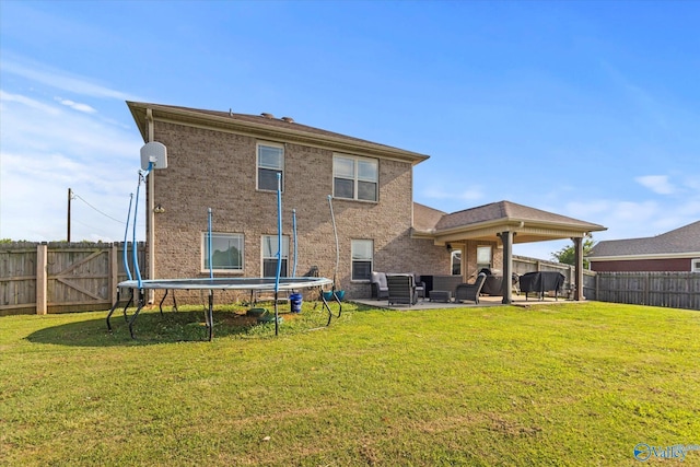 rear view of property with a patio area, a lawn, and a trampoline