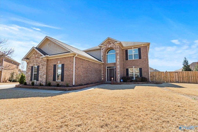 traditional home with brick siding, fence, and a front lawn