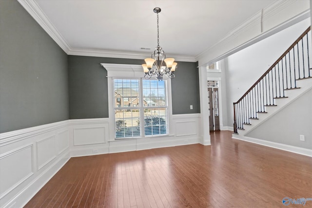 unfurnished dining area with visible vents, stairway, an inviting chandelier, ornamental molding, and wood finished floors