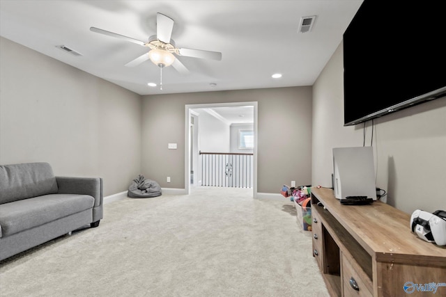 sitting room with baseboards, ceiling fan, visible vents, and light colored carpet