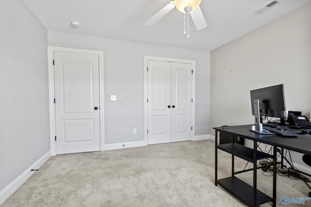 office featuring a ceiling fan, light colored carpet, visible vents, and baseboards