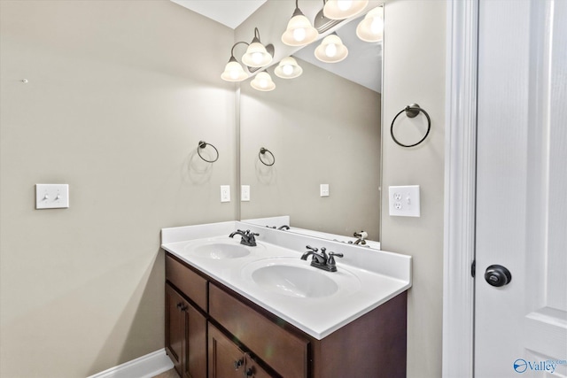 bathroom with a sink, baseboards, and double vanity