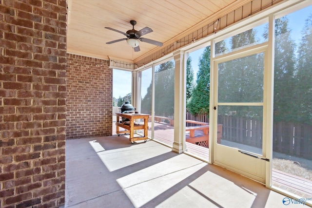 unfurnished sunroom featuring a ceiling fan, wooden ceiling, and plenty of natural light