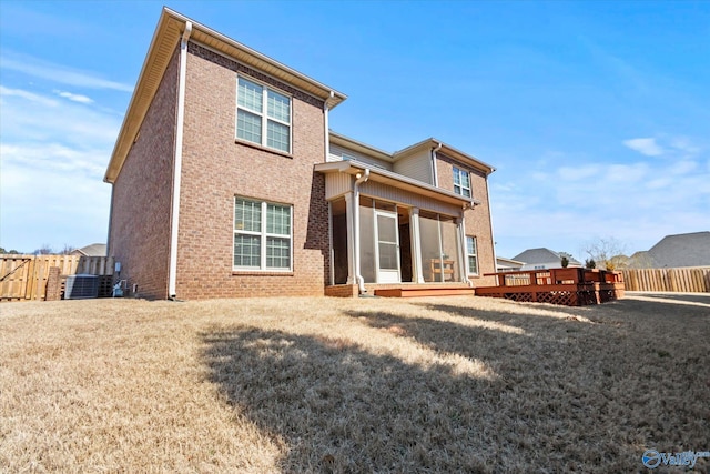 back of house featuring a deck, brick siding, a lawn, and fence