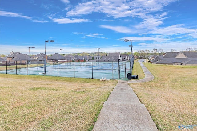 view of sport court featuring a residential view, a lawn, and fence