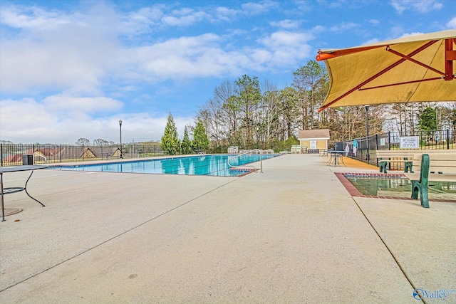 community pool featuring an outbuilding, fence, and a patio