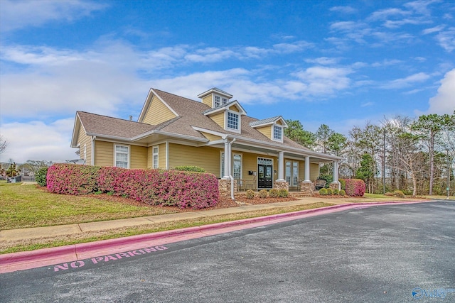 view of front of property with a shingled roof, a front yard, and covered porch