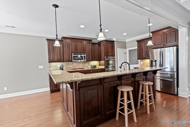 kitchen featuring a breakfast bar, stainless steel appliances, crown molding, and wood finished floors