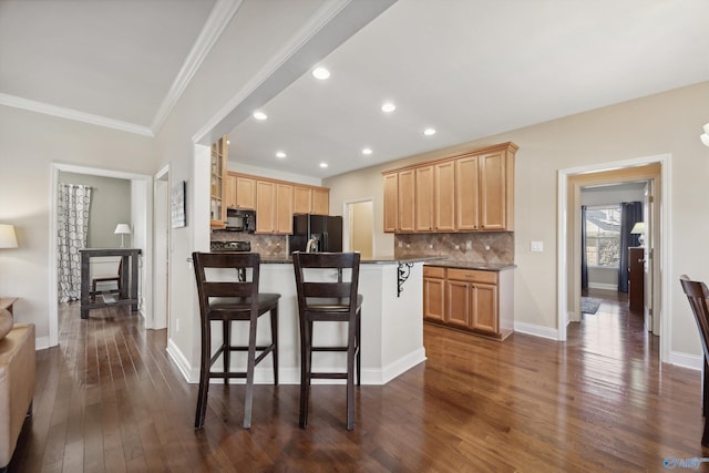 kitchen with black appliances, light brown cabinetry, backsplash, dark wood-style floors, and a breakfast bar area