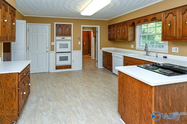 kitchen featuring brown cabinets, a sink, and white appliances