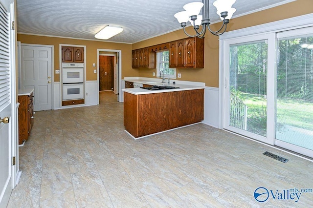 kitchen with double oven, brown cabinetry, a chandelier, and visible vents