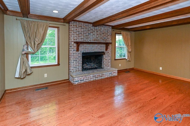 unfurnished living room with baseboards, beamed ceiling, wood finished floors, and visible vents