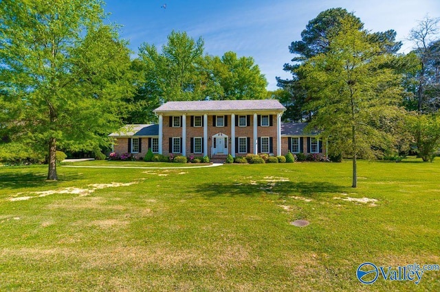 greek revival house featuring brick siding and a front yard