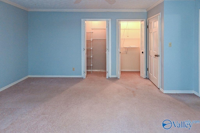 unfurnished bedroom featuring carpet floors, ornamental molding, multiple closets, and baseboards