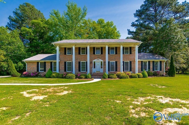 neoclassical / greek revival house with brick siding and a front yard