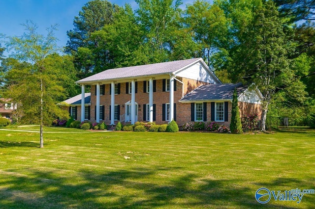 greek revival inspired property featuring brick siding and a front yard