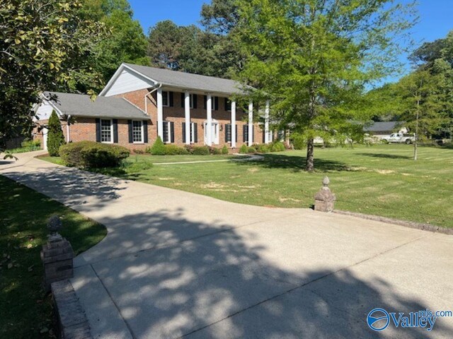 greek revival house featuring brick siding and a front lawn
