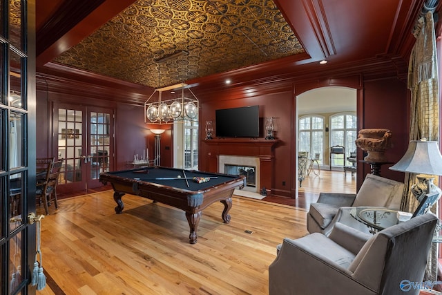 game room with a tray ceiling, crown molding, french doors, and a fireplace