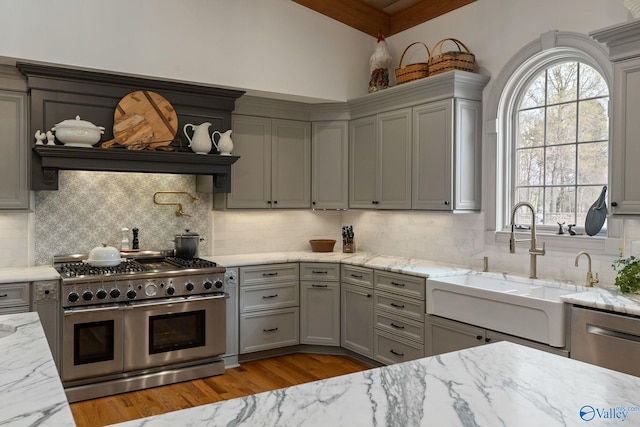 kitchen featuring appliances with stainless steel finishes, gray cabinets, sink, and light stone counters