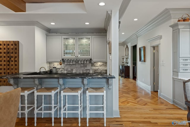 kitchen featuring kitchen peninsula, crown molding, a breakfast bar, and backsplash