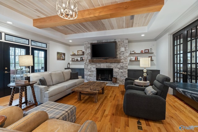 living room featuring a fireplace, a notable chandelier, light hardwood / wood-style floors, ornamental molding, and beamed ceiling