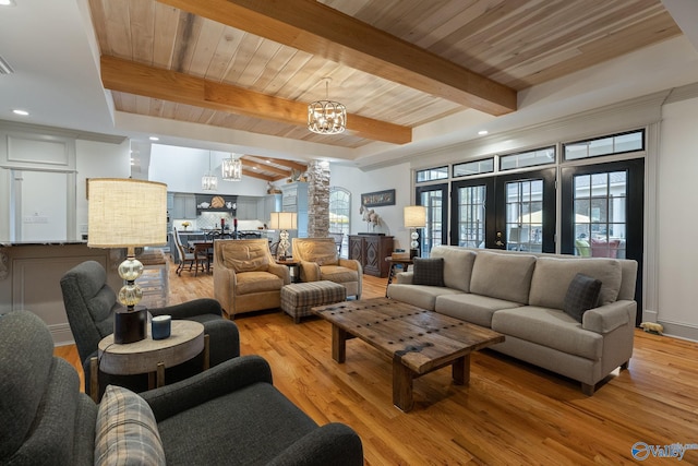 living room with beamed ceiling, light hardwood / wood-style floors, a chandelier, and wooden ceiling