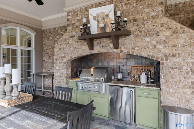 kitchen with green cabinetry, stainless steel fridge, sink, ornamental molding, and ceiling fan