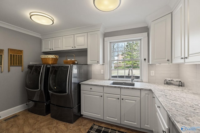 laundry area with cabinets, washing machine and dryer, crown molding, and sink